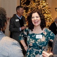 a group of people talking in front of Christmas tree